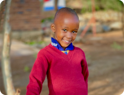 A young student standing in front of a bucket being filled with water from a pipe.