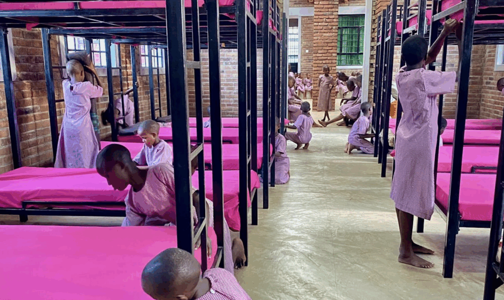 A room containing rows of bunk beds with young girls making them up