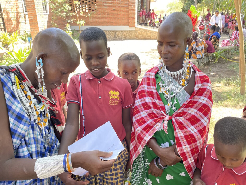 Students outside while an adult reads from a book