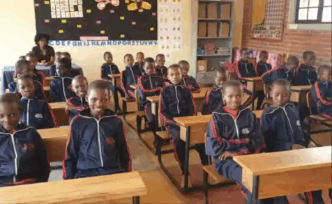 Students standing by their desks in a classroom