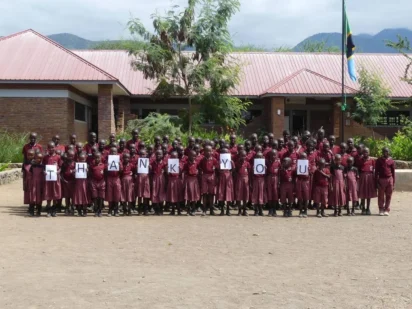 A large group of people standing outside holding up letters that spell out Thank You.