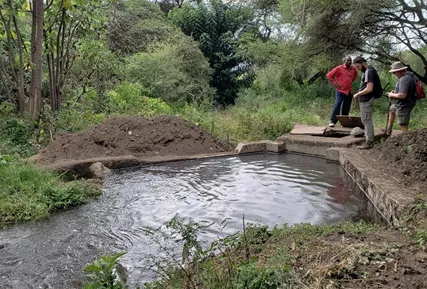 Brian Benham, Doug Belcik and community water manager at Engaruka Dam during 2018 pipeline route survey.